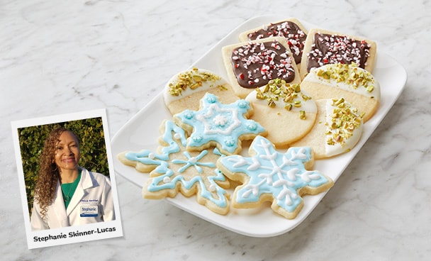 Photo of Stephanie Skinner-Lucas, MS, RDN, LD sitting on a table next to a plate of beautifully decorated sugar cookies.