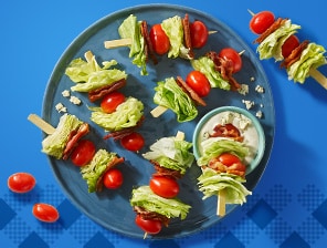 Iceberg lettuce, cherry tomatoes, bacon and salad dressing on skewers. Served alongside aplatter of grilled corn.