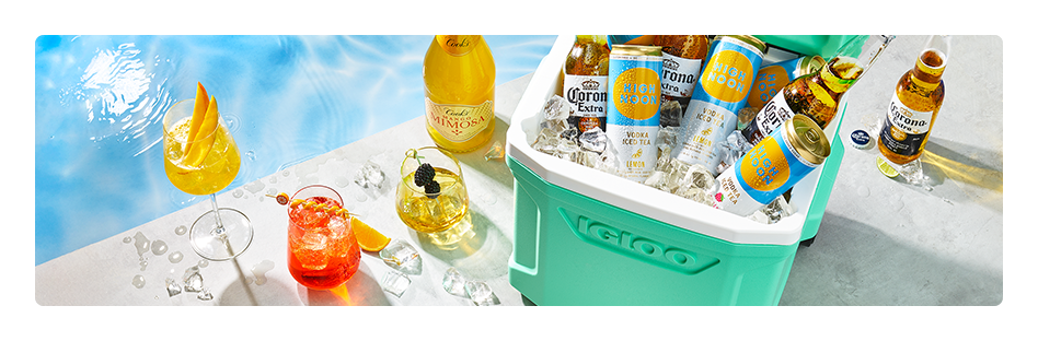 Colorful summer cocktails with fresh fruit garnish; Assorted bottles of beer and cans of seltzer.