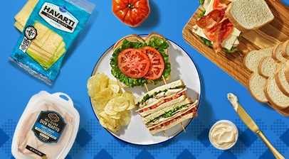 Turkey club sandwich cut in half and served with potato chips.