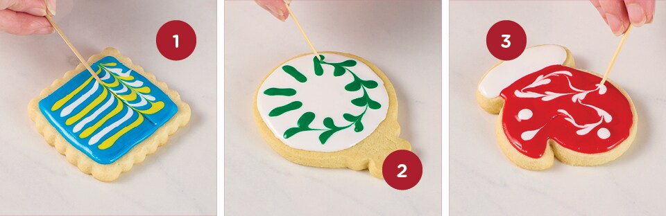 A series of three images of single sugar cookies showing how to use the toothpick method to decorate. The first image shows using the feathered look, the middle image shows the wreath method and the third image shows the marble method.