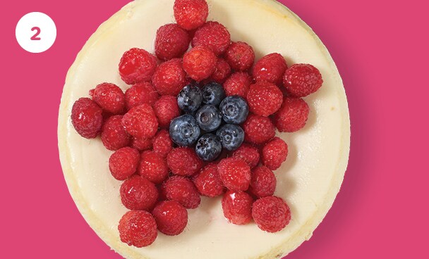 fresh berries in a flower shape on top of a plain cheesecake