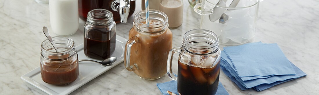 Mason jar cups with iced coffee and ice cubes Mason jar cups with iced coffee and ice cubes