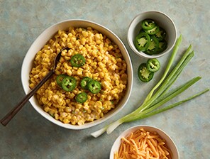Dish of Cheesy Jalapeño Corn topped with Jalapeño slices for garnish.